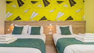 2 camas en una habitación con una pared amarilla y negra en The Auld Dubliner, en Dublín