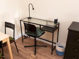 a glass desk with a chair and a lamp at Pass the Keys Great apt 20 mins central London in Surbiton