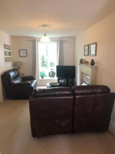 a living room with a leather couch and a television at Close to Jurassic Coast 3 Bed modern house in Wool