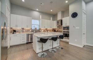 cocina grande con armarios blancos y taburetes de bar en Luxurious Med Cntr/NRG Townhome en Houston