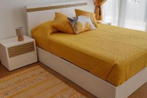 a bedroom with a bed with a yellow bedspread and a night stand at Sol e Mar by the airport in Santa Cruz