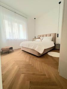 Habitación blanca con cama grande y suelo de madera. en Apartment Tivoli en Liubliana