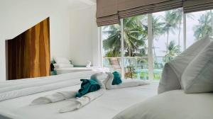 een kamer met witte bedden en een groot raam bij Villa LA Kurumba in Ambalangoda