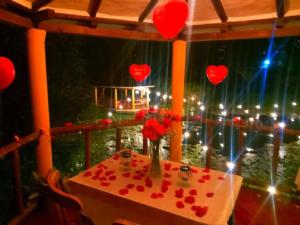 una mesa con un jarrón de corazones rojos en el balcón en Hotel Casa Cantabria Campestre en Villa de Leyva