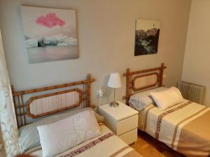 a bedroom with two beds and a lamp on a table at apartamento central in Ribadesella