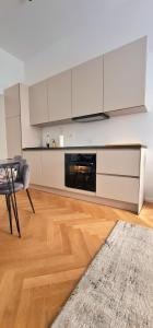 リュブリャナにあるApartment Tivoliの白いキャビネット、テーブル、ソファ付きのキッチンが備わります。