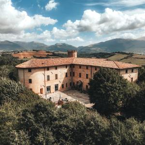 un gran edificio en una colina con montañas en el fondo en Castello di Baccaresca, en Branca