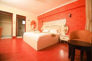 1 dormitorio con cama blanca y pared de ladrillo rojo en Gold Suite Hotel, en Nakuru