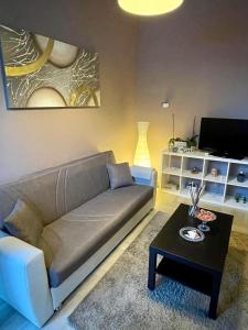 ein Wohnzimmer mit einem Sofa und einem Tisch in der Unterkunft Floris Home tra Mare e Montagna in Zafferana Etnea