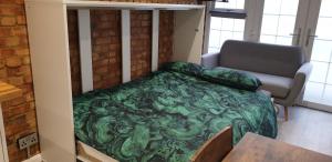 a bedroom with a green bed and a couch at Tiny home whole flat beach cabin in Southwick