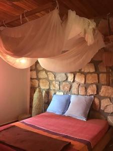 Bett in einem Zimmer mit einer Steinmauer in der Unterkunft Villa Kanto - Belle maison et jolie vue Mga centre in Mahajanga