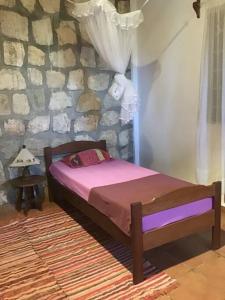 a bed in a room with a stone wall at Villa Kanto - Belle maison et jolie vue Mga centre in Mahajanga
