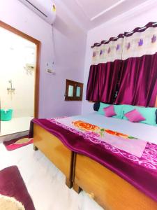 a bedroom with a bed with purple sheets and a window at Hostel shivshakti khajuraho in Khajurāho