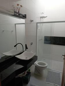 uma casa de banho com um lavatório, um chuveiro e um WC. em Chácara Horiental em Maringá