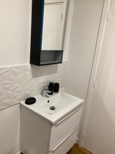 uma casa de banho branca com um lavatório e um espelho em Golf & Rempart em Angoulême