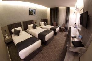 a hotel room with two beds and a television at Kaya Hotel Amman in Amman