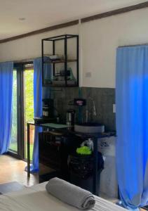 Torio的住宿－Sea view hills bungalow，一间带水槽和蓝色窗帘的浴室