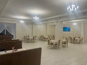 une salle à manger avec des tables, des chaises et des lustres dans l'établissement Grand Hotel, à Mohyliv-Podilʼsʼkyy