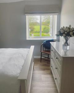 a bedroom with a bed and a desk with a vase of flowers at Winstitchen Cottage in Simonsbath