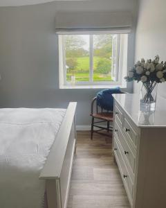 - une chambre avec un lit et un bureau avec un vase de fleurs dans l'établissement Winstitchen Cottage, à Simonsbath