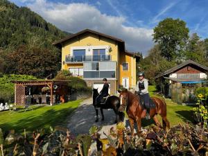 two people on horses in front of a house at Apartment Reißeck in Penk