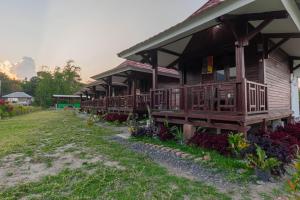 a house with wooden decks and a grass yard at Bale Gantar in Sembalun Lawang