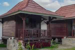 une maison en bois avec une terrasse couverte et un toit dans l'établissement Bale Gantar, à Sembalun Lawang