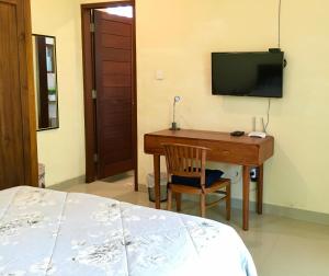 - une chambre avec un bureau, une télévision et un lit dans l'établissement Villa Jalak Kembar, à Canggu