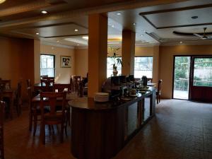 um restaurante com um bar e mesas e cadeiras em The Orchid Hotel em Phuntsholing