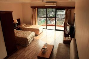 um quarto de hotel com duas camas e uma televisão em The Orchid Hotel em Phuntsholing