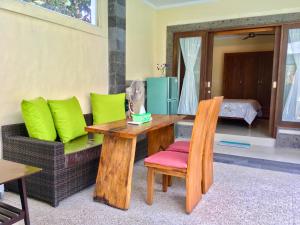 a wooden table and a chair and a couch at Villa Jalak Kembar in Canggu