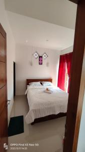 ein Schlafzimmer mit einem großen Bett mit einem roten Vorhang in der Unterkunft Jatisela Homestay5 in Midang