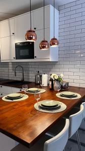 a kitchen with a wooden table with plates and wine glasses at APARTMENT KRISTINA in Dunajská Streda