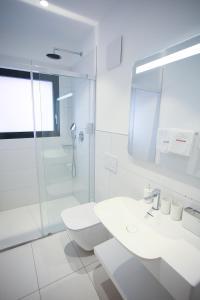 een witte badkamer met een wastafel en een douche bij Hotel Bellavista Locarno in Locarno