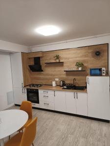 a kitchen with white cabinets and a table with chairs at Apartament Genius 2 in Ploieşti