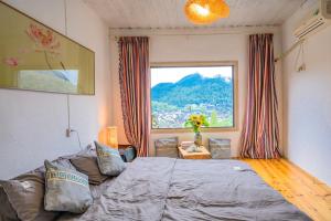 um quarto com uma cama e uma grande janela em 云起山居庭院观景民宿 em Fenghuang