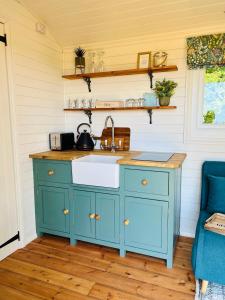 una cucina con mobile blu e lavandino di The Green Hut a Battle