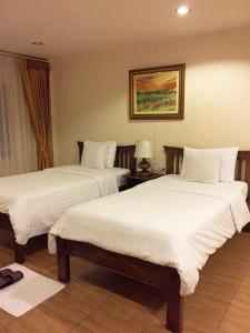 ein Hotelzimmer mit 2 Betten mit weißer Bettwäsche in der Unterkunft Chan Chiangmai House in Chiang Mai