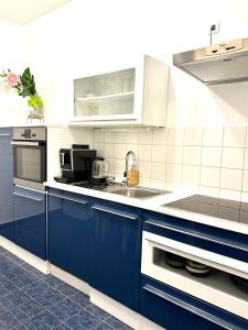 een keuken met blauwe kasten en een wastafel bij City center Apartment in Wenen