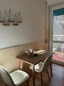 stół jadalny z 2 białymi krzesłami i stołem w obiekcie Casa VerdeMare w mieście Lido di Ostia