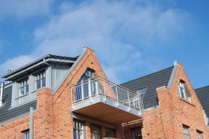 a brick building with a balcony on top of it at Bootshaus SunDeck - Strandnah in den Dünen in Wangerooge