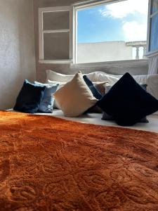 eine Gruppe von Kissen auf einem Bett mit einem Fenster in der Unterkunft House with sea view in Kasbah in Tangier