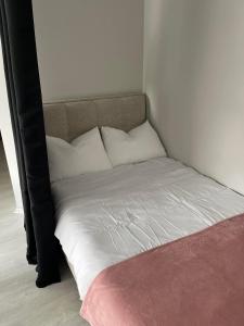 1 cama con sábanas blancas y almohadas en una habitación en Apartment Aria, en Skopje