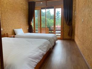 dwa łóżka w pokoju z dużym oknem w obiekcie Bac Ha Legend Home w mieście Bac Ha