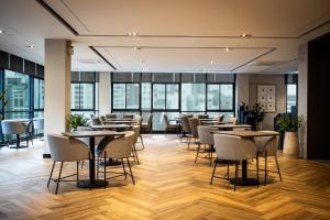 a restaurant with tables and chairs and windows at SAM E Hotel Bangkok Sathorn in Bangkok