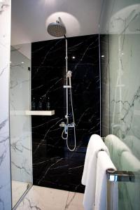 a bathroom with a shower with a black marble wall at SAM E Hotel Bangkok Sathorn in Bangkok