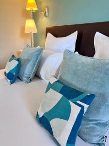 a bed with blue and white pillows on it at H&ocirc;tel Les Vieilles Tours Rocamadour in Rocamadour