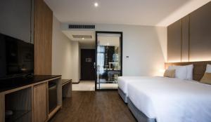 SAM E Hotel Bangkok Sathorn في بانكوك: غرفه فندقيه سرير وتلفزيون