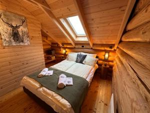 1 dormitorio en una cabaña de madera con 1 cama y zapatillas en Rönk Relax, en Miskolc