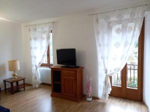 a living room with white curtains and a television at Casa Nonna Rosa in Ponte in Valtellina